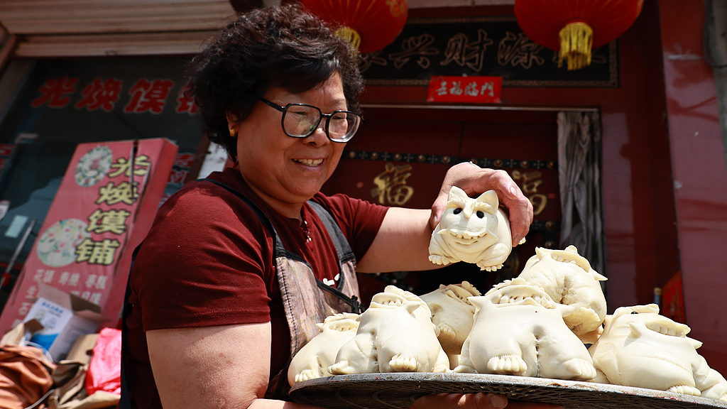 An inheritor of Jinnan Huamo showcases freshly steamed tiger buns at a huamo shop in Yuncheng, Shanxi Province, on May 28, 2025./VCG